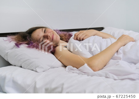 Teen girl waking up in the morning lying on pillow in bed Teen girl waking up in the morning lying on pillow in bed 67225450