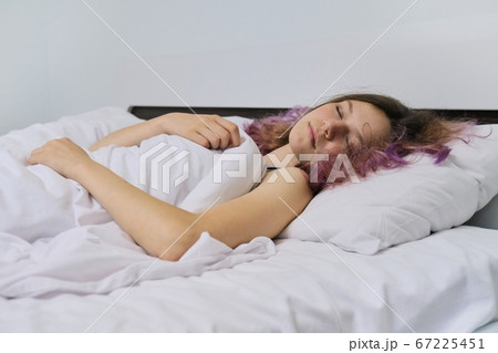 Teen girl sleeping at home in bed 67225451