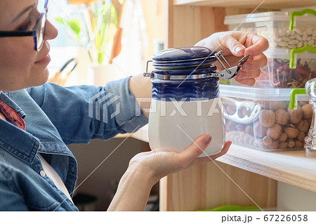 Woman in the kitchen with can of dry mint, food storage, pantry 67226058