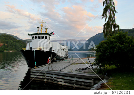 ノルウェー　ハダンゲルフィヨルド、ウルヴィク地区のホテル南東の波止場より白夜の黄昏の小型遊覧船を望む 67226231