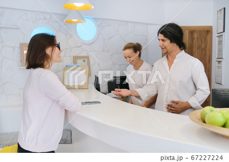 Reception at resort hotel. Guest checking in at the front desk Reception at resort hotel. Guest checking in at the front desk 67227224