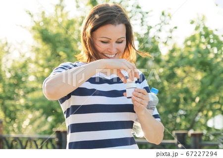 Outdoor middle-aged woman with medicine, vitamins, supplements 67227294