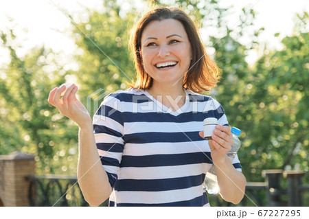 Outdoor middle-aged woman with medicine, vitamins, supplements Outdoor middle-aged woman with medicine, vitamins, supplements 67227295