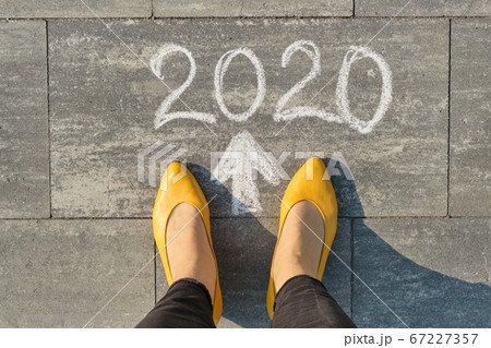 2020 arrow forward, written on gray sidewalk with woman legs, top view 2020 arrow forward, written on gray sidewalk with woman legs, top view 67227357