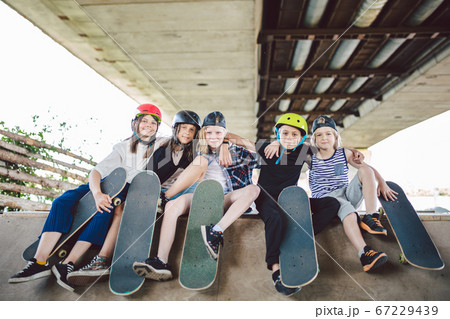 Extreme sport in city. Skateboarding Club for children. Group friends posing on ramp at skatepark. Early adolescence in skate training. Friends skateboarders on street platform for skating on board 67229439