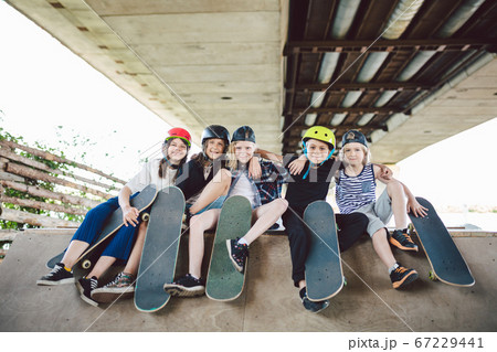 Happy friends in city park for extreme sports. Little ones having fun on skating ramp outdoor . Youth and friendship. Caucasian riders having fun together on sports urban area for skateboarding Happy friends in city park for extreme sports. Little ones having fun on skating ramp outdoor . Youth and friendship. Caucasian riders having fun together on sports urban area for skateboarding 67229441