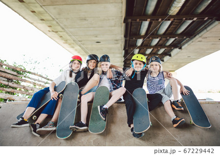 Extreme sport in city. Skateboarding Club for children. Group friends posing on ramp at skatepark. Early adolescence in skate training. Friends skateboarders on street platform for skating on board 67229442