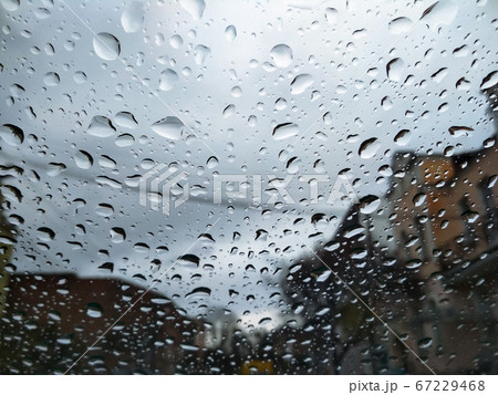 City street seen through rain drops on the car windshield. Bad Autumn weather in Rainy day. Windshield window of car with raindrops on glass windscreen. City street seen through rain drops on the car windshield. Bad Autumn weather in Rainy day. Windshield window of car with raindrops on glass windscreen. 67229468