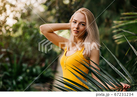 Woman in swimsuit on tropical plants background Woman in swimsuit on tropical plants background 67231234