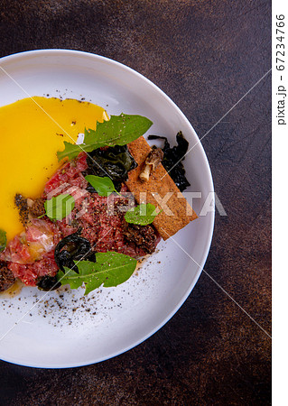 A beef tartar on a white plate against a dark background. Master class in the kitchen. The process 67234766