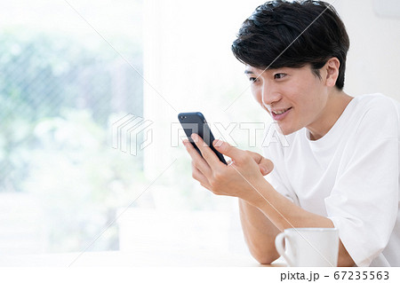 スマホを見ながら会話する若い男性 スマホを見ながら会話する若い男性 67235563