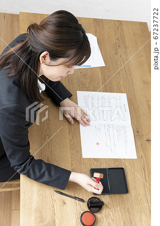 ビジネススーツで机で書類に捺印する女性 ビジネススーツで机で書類に捺印する女性 67237722