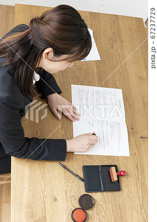 ビジネススーツで机で書類に捺印する女性 ビジネススーツで机で書類に捺印する女性 67237729