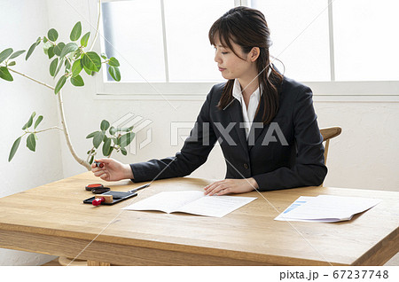 ビジネススーツで机で書類に捺印する女性 ビジネススーツで机で書類に捺印する女性 67237748
