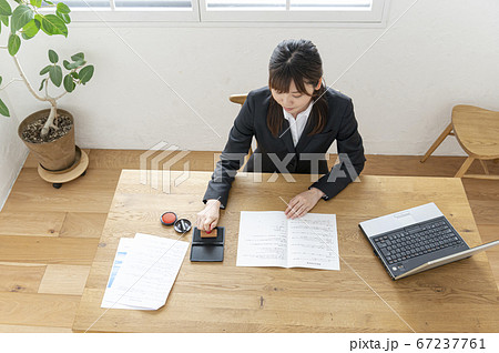 ビジネススーツで机で書類に捺印する女性 ビジネススーツで机で書類に捺印する女性 67237761
