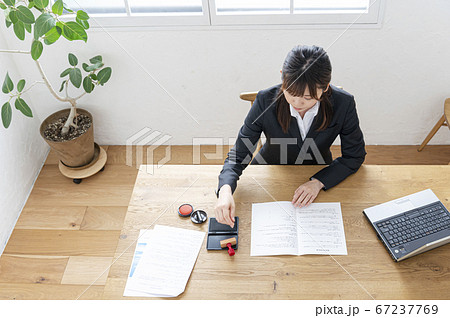 ビジネススーツで机で書類に捺印する女性 ビジネススーツで机で書類に捺印する女性 67237769