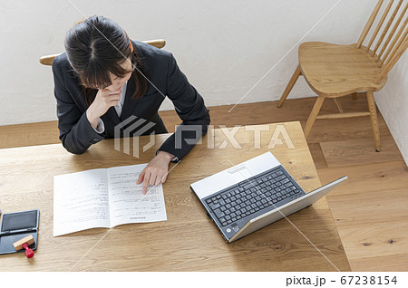 ビジネススーツで机で書類に捺印する女性 67238154