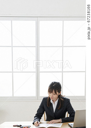 ビジネススーツで机で書類に捺印する女性 ビジネススーツで机で書類に捺印する女性 67238166