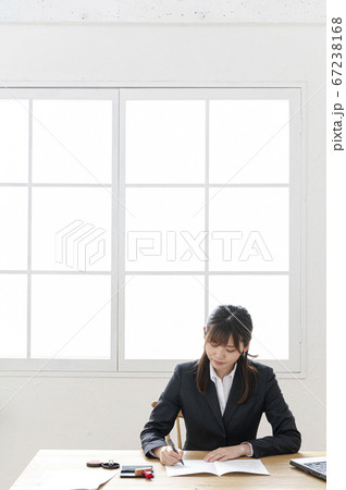 ビジネススーツで机で書類に捺印する女性 67238168