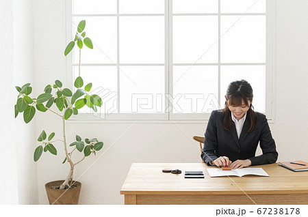 ビジネススーツで机で書類に捺印する女性 67238178