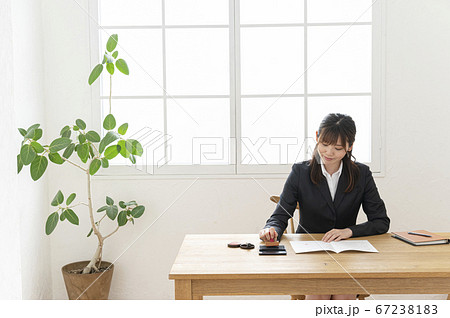 ビジネススーツで机で書類に捺印する女性 67238183