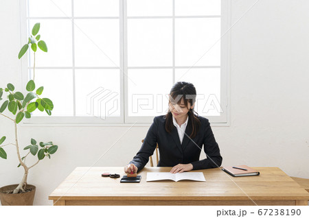 ビジネススーツで机で書類に捺印する女性 67238190
