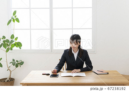 ビジネススーツで机で書類に捺印する女性 ビジネススーツで机で書類に捺印する女性 67238192