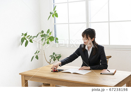 ビジネススーツで机で書類に捺印する女性 67238198