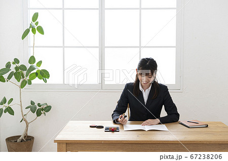 ビジネススーツで机で書類に捺印する女性 ビジネススーツで机で書類に捺印する女性 67238206