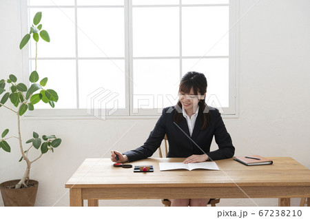 ビジネススーツで机で書類に捺印する女性 ビジネススーツで机で書類に捺印する女性 67238210