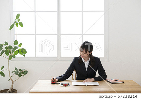ビジネススーツで机で書類に捺印する女性 ビジネススーツで机で書類に捺印する女性 67238214