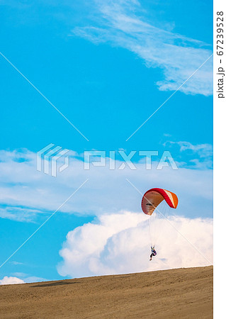 鳥取砂丘でパラグライダーを楽しむ若者たちの写真素材