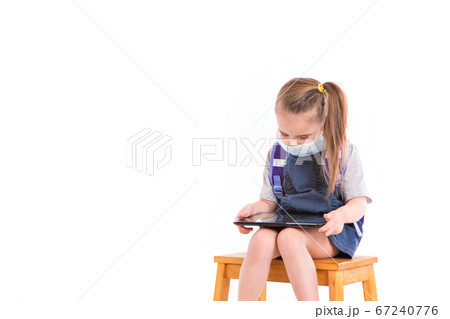 first-grader in medical mask learns to read. little girl on home distance learning. child in medical mask works at laptop and books. doing homework. isolated on white background. knowledge day first-grader in medical mask learns to read. little girl on home distance learning. child in medical mask works at laptop and books. doing homework. isolated on white background. knowledge day 67240776