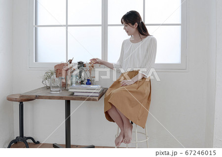 窓際に座ってくつろぐ若い女性 67246015