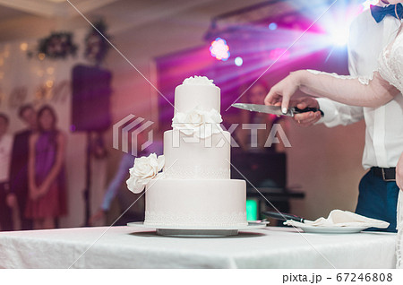 wedding ceremony. the bride and groom make their first case together, cut the white wedding cake wedding ceremony. the bride and groom make their first case together, cut the white wedding cake 67246808