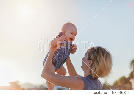 Young woman holding her happy smiling baby girl on hands against blue sky. Young woman holding her happy smiling baby girl on hands against blue sky. 67246810