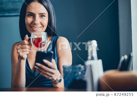 Woman sitting at the table and holding cup of tea 67249255