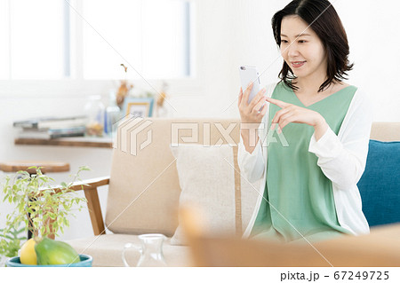 リビングでスマホを操作するミドル女性 リビングでスマホを操作するミドル女性 67249725