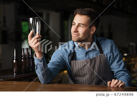 Check the cleanliness of beer glass. Satisfied barman looks at empty glass Check the cleanliness of beer glass. Satisfied barman looks at empty glass 67249896