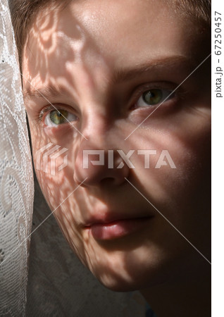 Woman With Shadows From A Lace Curtain On Her Face 67250457
