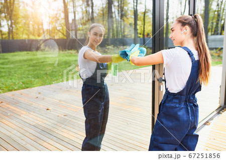 Cleaning concept. Young caucasian woman washing window outdoors Cleaning concept. Young caucasian woman washing window outdoors 67251856
