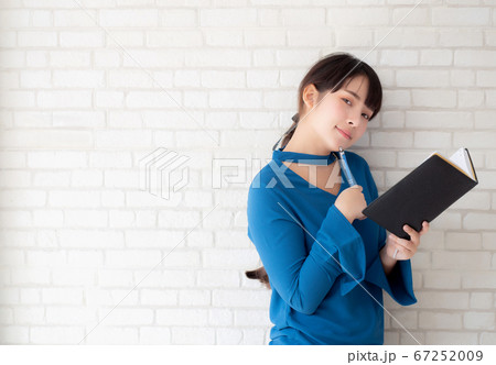 Beautiful asian woman smiling standing thinking and writing notebook. 67252009