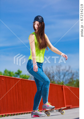 Teen girl skater riding skateboard on street. 67254219