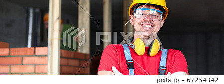 Happy builder stands near brickwork and smiles Happy builder stands near brickwork and smiles 67254342