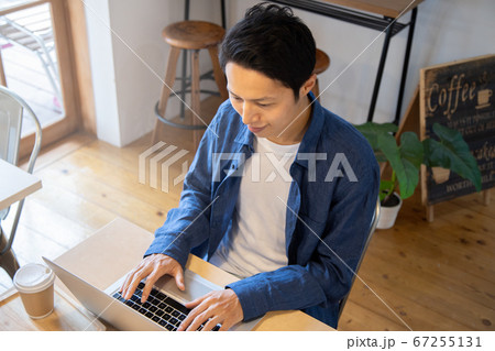 カフェでパソコンを操作する若い男性　ノマドワーク 67255131