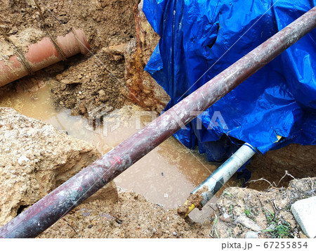 KUALA LUMPUR, MALAYSIA -JUNE 02, 2017: Underground utility and services pipe laid by workers in the trenches at the construction site. Installation of stop cork valve and joint in progress. KUALA LUMPUR, MALAYSIA -JUNE 02, 2017: Underground utility and services pipe laid by workers in the trenches at the construction site. Installation of stop cork valve and joint in progress. 67255854