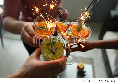 Goup of people holding cocktails in their hands with sparklers Goup of people holding cocktails in their hands with sparklers 67256363