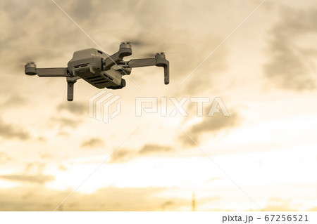 夕暮れの中で空撮するドローン 67256521