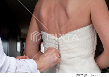 Bridesmaid is lacing white wedding dress for bride.  67262026