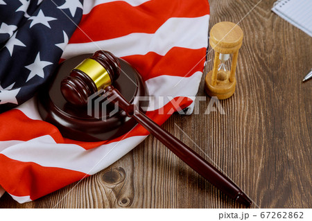 Hourglass measuring the US judge legal office with judge's gavel on American flag table Hourglass measuring the US judge legal office with judge's gavel on American flag table 67262862